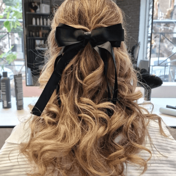 Professional hairstyling on a client's hair, creating a stylish and trendy hairstyle in a modern salon. - center side with ribbon on hair